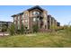 Modern brown brick apartment building featuring black accents, balconies and beautifully manicured lawn at 6619 E Lowry Blvd # 101, Denver, CO 80230