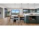 Open kitchen with island, modern pendant lights, wood table, and sliding doors to the patio at 7267 Comanche Ct, Larkspur, CO 80118