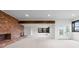 Spacious living room with brick fireplace and wood beam, with bright light coming from windows and glass patio doors at 7267 Comanche Ct, Larkspur, CO 80118
