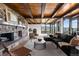 A spacious living room is complimented by a stone fireplace, wood beam ceiling, and large windows at 7267 Comanche Ct, Larkspur, CO 80118