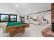 Open-concept living room featuring pool table, modern furniture, brick fireplace and bright natural light from outside at 7267 Comanche Ct, Larkspur, CO 80118