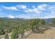 Scenic backyard view of a mountainside with sparse trees under a partly cloudy sky at 1015 Nob Hill Rd, Evergreen, CO 80439