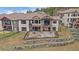 Two-story home with balconies, a patio, tiered stone landscaping, and iron fencing at 1015 Nob Hill Rd, Evergreen, CO 80439
