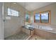 Bright bathroom featuring a glass-enclosed shower, soaking tub, and window offering scenic views at 1015 Nob Hill Rd, Evergreen, CO 80439