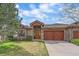 Charming stone home featuring a wooden garage door and a well manicured front yard at 1015 Nob Hill Rd, Evergreen, CO 80439