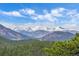 Expansive mountain range vista with evergreen forests below and snow capped peaks beyond at 1015 Nob Hill Rd, Evergreen, CO 80439