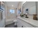 Modern bathroom features a bathtub, gray tile accents, and a sink with a white vanity and black hardware at 2430 Ames St, Edgewater, CO 80214