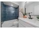 Bathroom featuring a bathtub, decorative blue tile accents, and sink with a white vanity and matte black hardware at 2430 Ames St, Edgewater, CO 80214