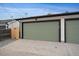 A detached two car garage with sage green doors sits at the end of a concrete drive way at 2430 Ames St, Edgewater, CO 80214