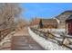 Paved path winds through winter landscape, alongside wooden fences and historic buildings at 810 Meadow Run, Golden, CO 80403