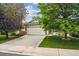Charming home exterior featuring a two-car garage, well-manicured lawn, and mature trees at 11418 Macon St, Commerce City, CO 80640