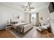 Staged bedroom with hardwood floors, area rug, a ceiling fan, neutral walls, and a cozy seating area near the window at 11418 Macon St, Commerce City, CO 80640