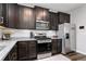 Well-lit kitchen features dark wood cabinets, stainless steel appliances, and granite countertops at 14836 Jersey Dr, Mead, CO 80542