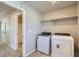 Well-lit laundry room with a washer, dryer, storage shelf, and access to the bathroom at 17467 E 89Th Way, Commerce City, CO 80022