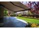 Spacious stone patio with a retractable awning provides shade overlooking a lush lawn at 9445 Aspen Hill Cir, Lone Tree, CO 80124