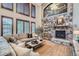 Open living room with vaulted ceilings, stone fireplace, built-in bar, and an oversized window at 9445 Aspen Hill Cir, Lone Tree, CO 80124