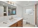 Bright bathroom featuring a wooden vanity, white countertops, and modern fixtures at 11900 W 18Th Ave, Lakewood, CO 80215
