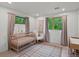 Cozy Bedroom with warm carpet, crib, rocking chair, and curtains framing verdant view at 11900 W 18Th Ave, Lakewood, CO 80215