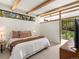 Bright bedroom featuring beam ceiling, with large windows and access to exterior at 11900 W 18Th Ave, Lakewood, CO 80215