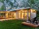 An exterior evening shot of the modern home featuring a covered patio, inviting lights, and a well-manicured backyard at 11900 W 18Th Ave, Lakewood, CO 80215
