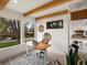 Bright home office featuring beam ceiling, modern desk, and view of exterior landscape at 11900 W 18Th Ave, Lakewood, CO 80215