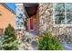 Inviting front porch featuring brick accents, manicured bushes, and a vibrant red door at 1909 Alpine Dr, Erie, CO 80516