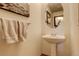 Well-lit powder room with modern fixtures, pedestal sink, towel bar, and decorative mirror at 1909 Alpine Dr, Erie, CO 80516