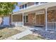 Inviting covered front porch with brick facade, white railing, and a double door entrance at 8102 S Zephyr St, Littleton, CO 80128