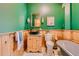 Unique bathroom featuring a soaking tub, wood paneling, green walls, and decorative fixtures at 1928 S Washington St, Denver, CO 80210