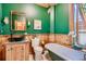 Unique bathroom featuring a soaking tub, wood paneling, green walls, and decorative fixtures at 1928 S Washington St, Denver, CO 80210