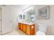 Bathroom with double sinks and wooden cabinets featuring a toilet with neutral tile flooring at 9758 Laredo St # 22D, Commerce City, CO 80022