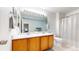 Bright bathroom with double vanity, a large mirror, and a tiled shower at 9758 Laredo St # 22D, Commerce City, CO 80022