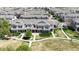 An aerial view shows the exterior of modern townhomes with manicured lawns and charming curb appeal in a well-planned community at 9758 Laredo St # 22D, Commerce City, CO 80022