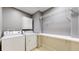 Functional laundry room featuring a white washer, dryer, storage cabinets, and a folding shelf at 9758 Laredo St # 22D, Commerce City, CO 80022