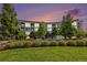 Modern condo building with lush landscaping and a colorful dusk sky at 2958 Syracuse St # 403, Denver, CO 80238