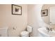 Bright half bath features neutral paint and decor, a white toilet and sink with decorative art at 20942 E Hampden Pl, Aurora, CO 80013