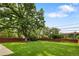 Spacious backyard with lush green grass, large trees, and a wooden fence at 1840 E 84Th Ave, Denver, CO 80229