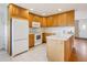 Functional kitchen with wooden cabinetry, white appliances, and breakfast bar seating at 1840 E 84Th Ave, Denver, CO 80229