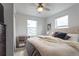 Bright bedroom with a plush bed, soft lighting from a ceiling fan and bedside lamp, and two windows at 2829 W 53Rd Ave # 104, Denver, CO 80221