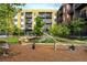 Playground with slide, climbing structure, seesaw, and tire swing surrounded by lovely landscaping at 2829 W 53Rd Ave # 104, Denver, CO 80221