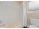 Clean bathroom with white tile walls, bathtub, toilet, and a window for natural light at 10294 Spotted Owl Ct, Highlands Ranch, CO 80129