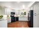 Modern kitchen featuring white cabinets, dark appliances, hardwood floors, and a bright window at 3285 Balsam St, Wheat Ridge, CO 80033