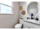 Stylish powder room with round mirror, granite countertop, and natural decor at 265 Upper Glenway, Palmer Lake, CO 80133
