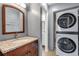 Bathroom vanity with granite countertop, wooden cabinets and a stacked washer and dryer unit at 2929 W Floyd Ave # 217, Denver, CO 80236