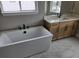Elegant bathroom featuring a freestanding soaking tub, modern fixtures, vanity with drawers, and designer tile flooring at 5591 Farrier Pt, Castle Rock, CO 80104