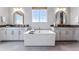 Bright bathroom featuring a soaking tub, double vanities with gray countertops, and stylish gold accents at 5591 Farrier Pt, Castle Rock, CO 80104