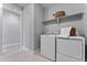 Bright laundry room featuring a white washer and dryer, white tiling, and a large storage shelf at 5591 Farrier Pt, Castle Rock, CO 80104