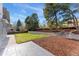 Large backyard featuring a well-maintained lawn, mature trees, and stone accents at 2477 S Dover Way, Lakewood, CO 80227