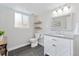 Bright bathroom with a modern vanity, a stylish mirror, wood shelves, and a toilet, enhanced by natural light from the window at 2477 S Dover Way, Lakewood, CO 80227