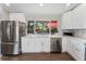 Well-lit kitchen with white cabinets, stainless steel appliances, and a view of the backyard through a large window at 2477 S Dover Way, Lakewood, CO 80227